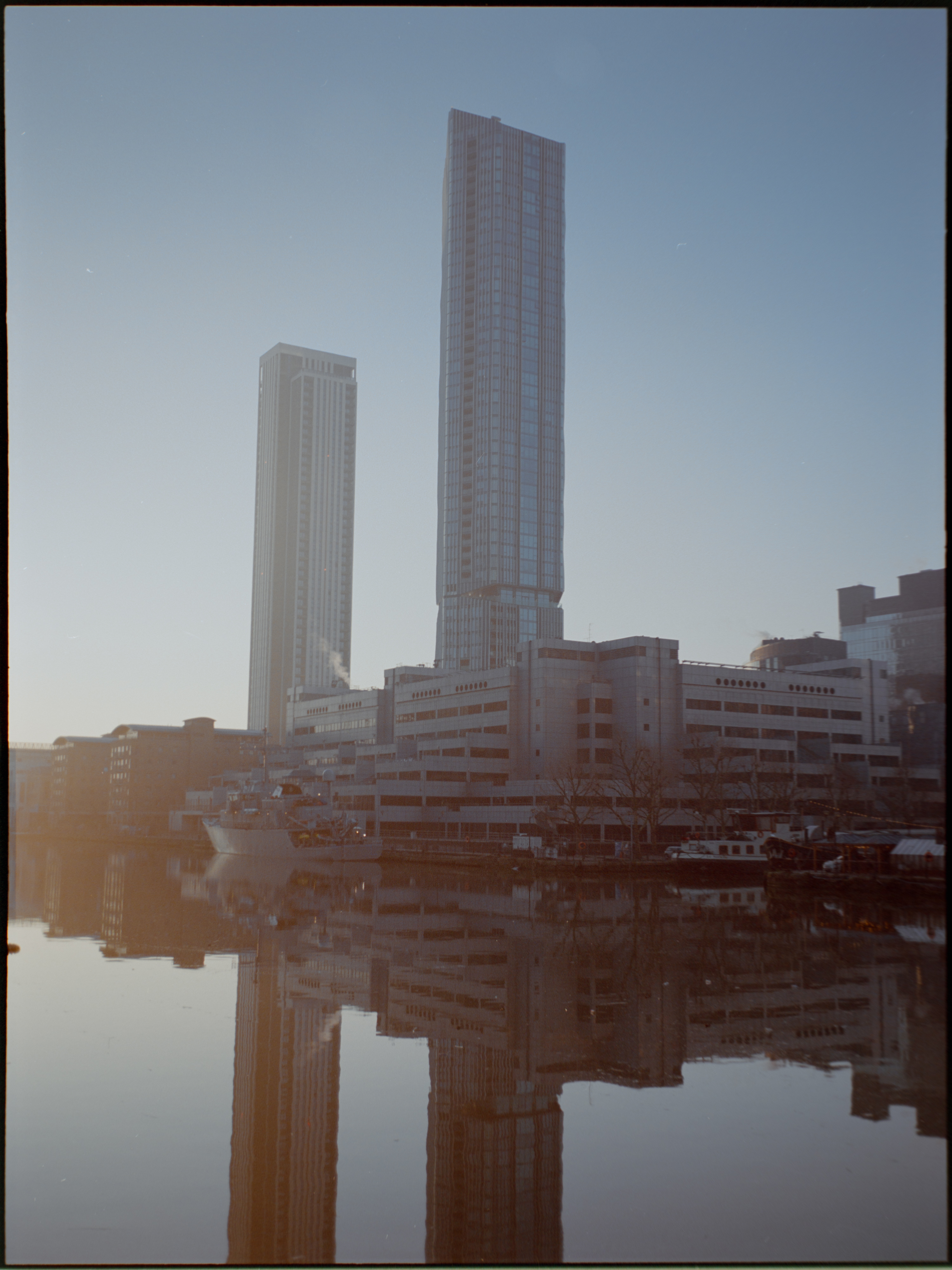 Person walking near modern building entrance in Canary Wharf — film photography London