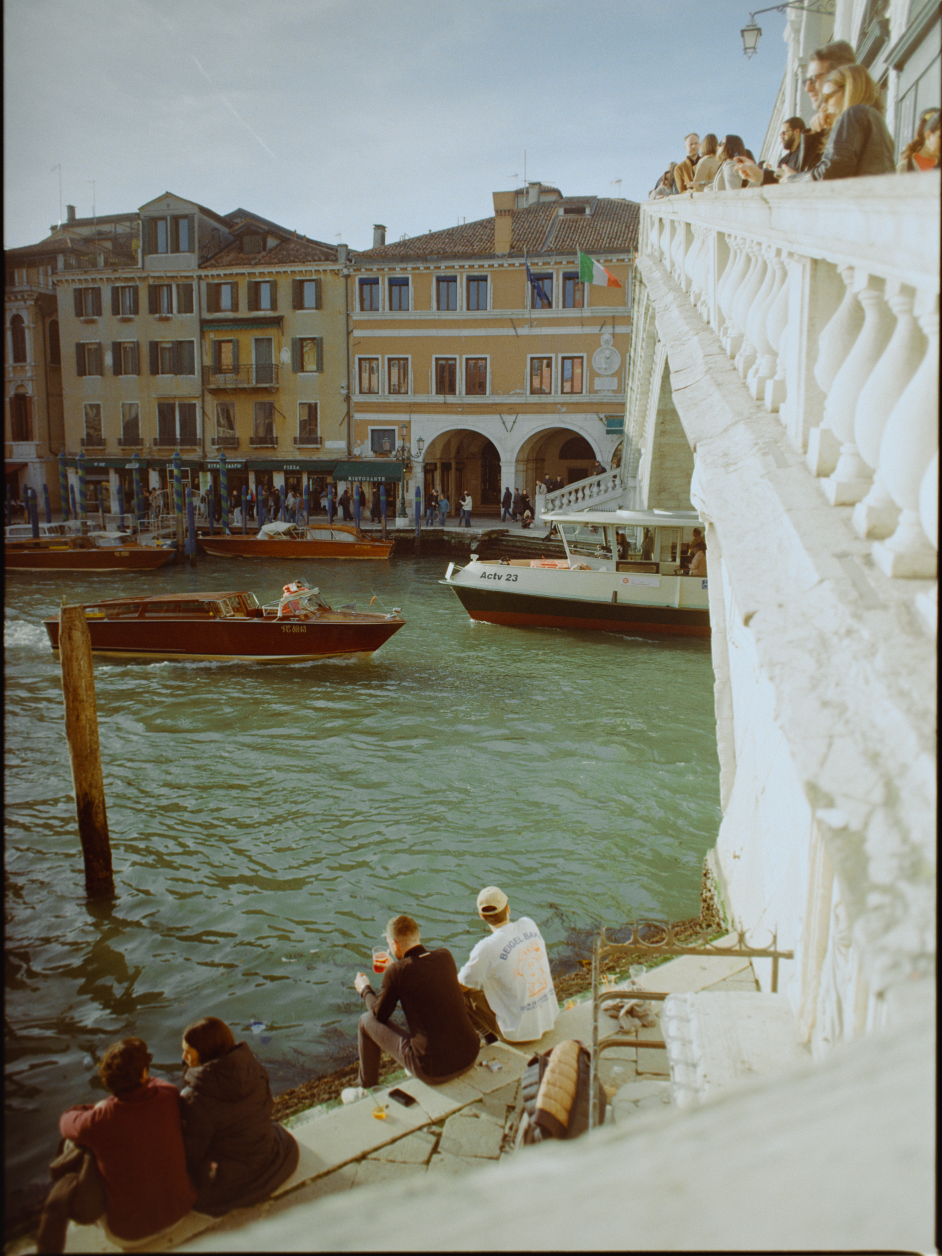 View from the Rialto Bridge looking down at young people sitting by the canal — Venice on Kodak Gold 200