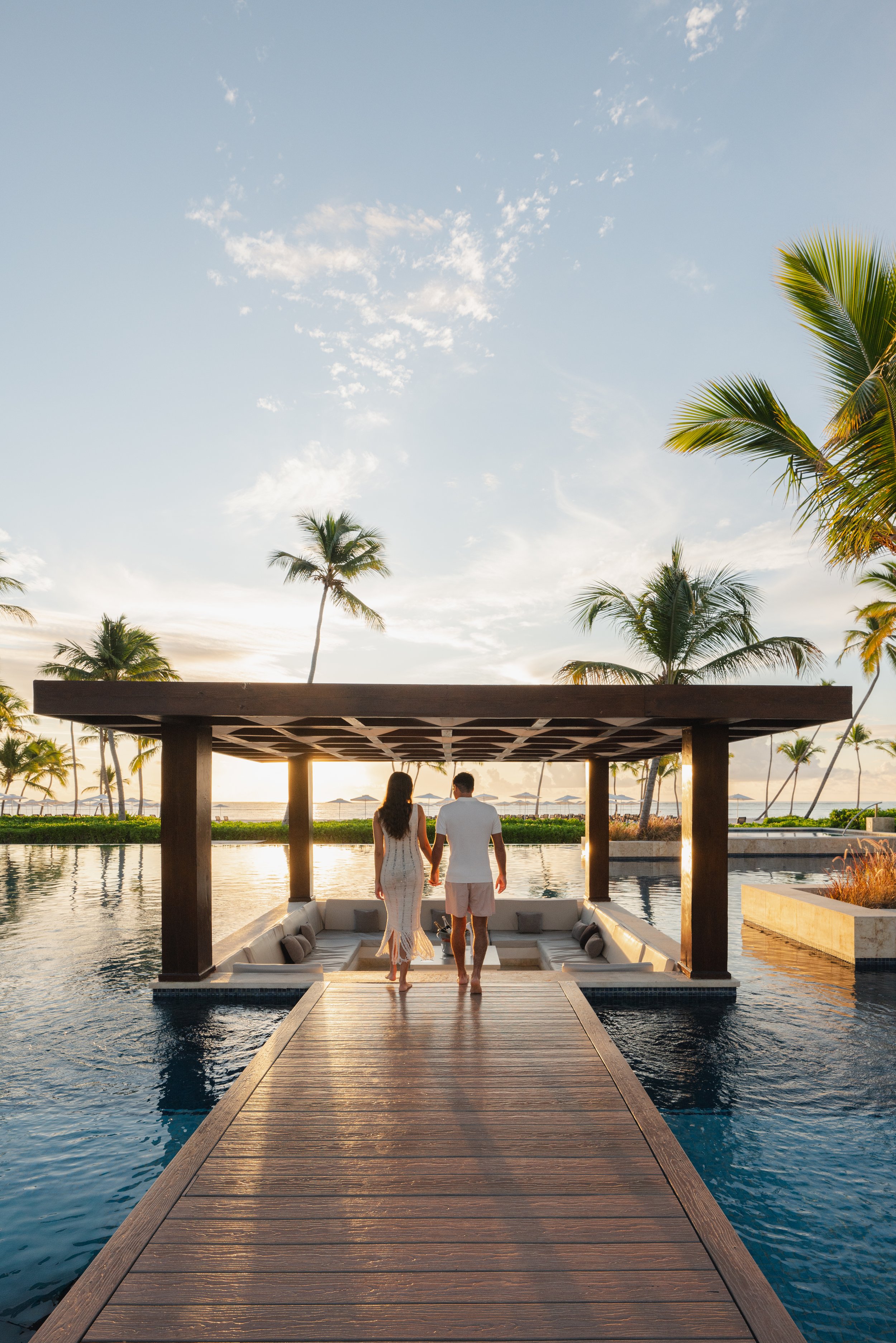 Couple at infinity pool sunrise tropical resort, lifestyle photography London