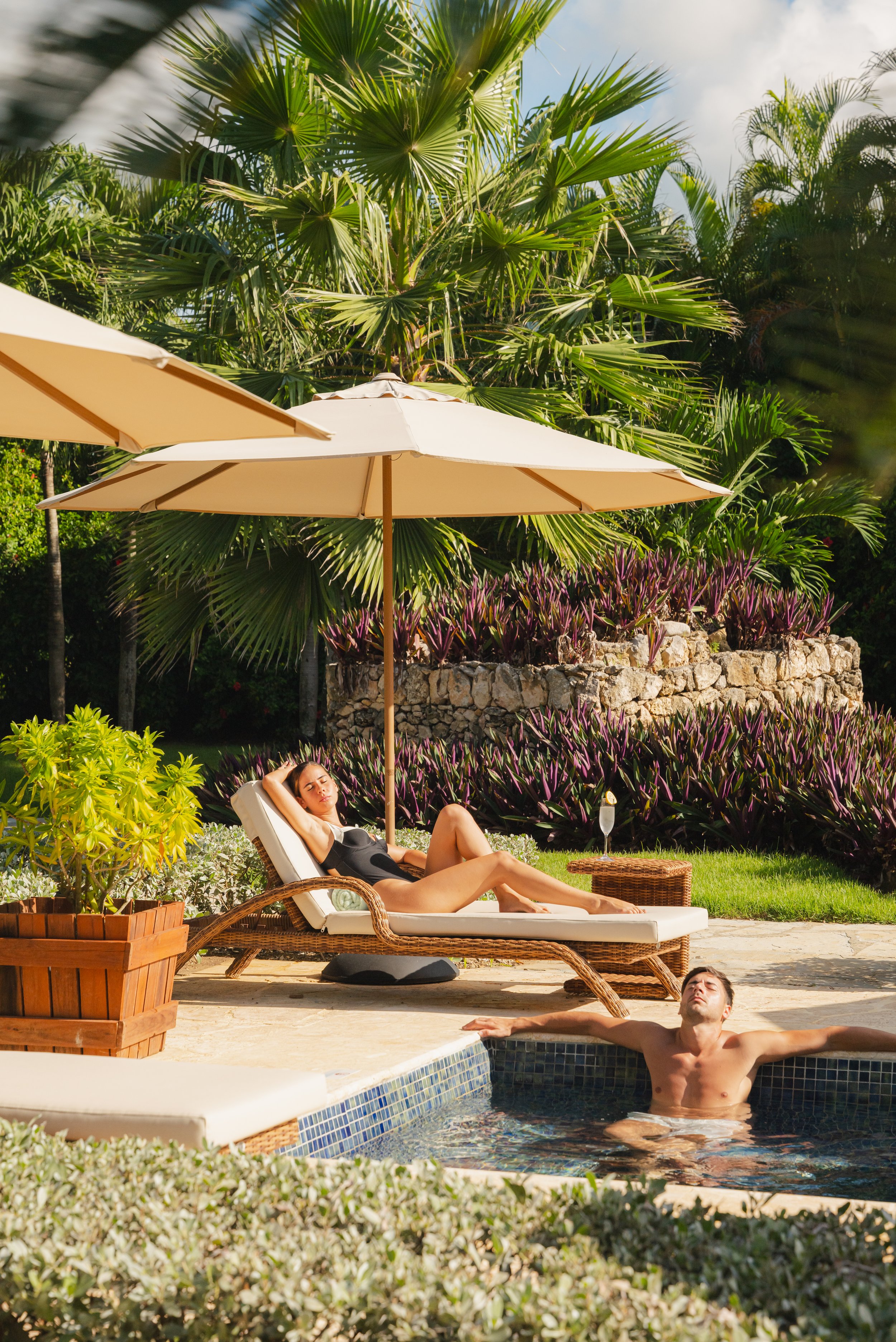 Couple poolside sun loungers parasol tropical garden Dominican Republic